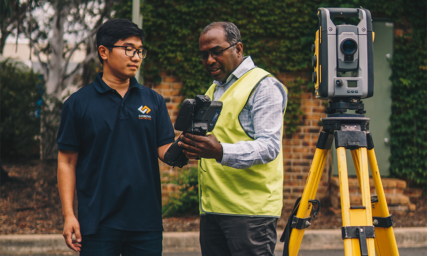 Two people working with surveying equipment.