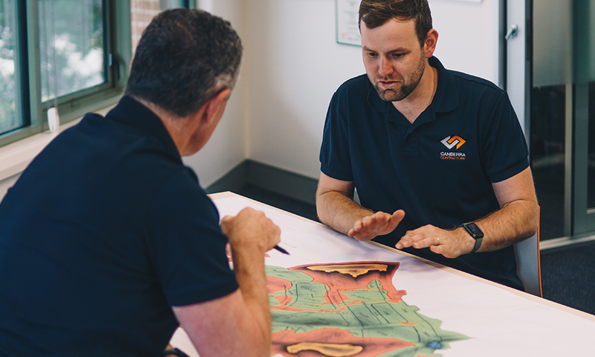 Two people seated at a table looking at a map.